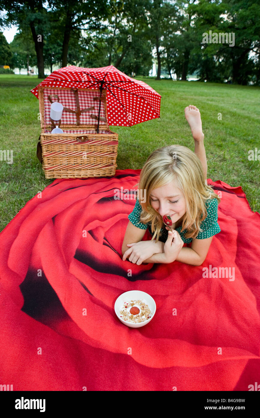 Una ragazza con una ciotola di yogurt, granola e fragole in un picnic Foto Stock