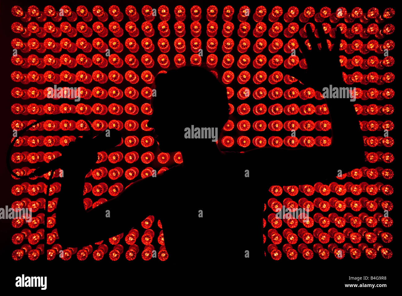 Silhouette di un cantante di fronte a luci rosse Foto Stock