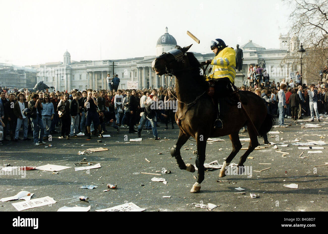 Dimostrazione di imposta di polling Marzo 1990 Demonstrator getta un pezzo di legno al funzionario di polizia a cavallo in Trafalgar Square Riot Foto Stock