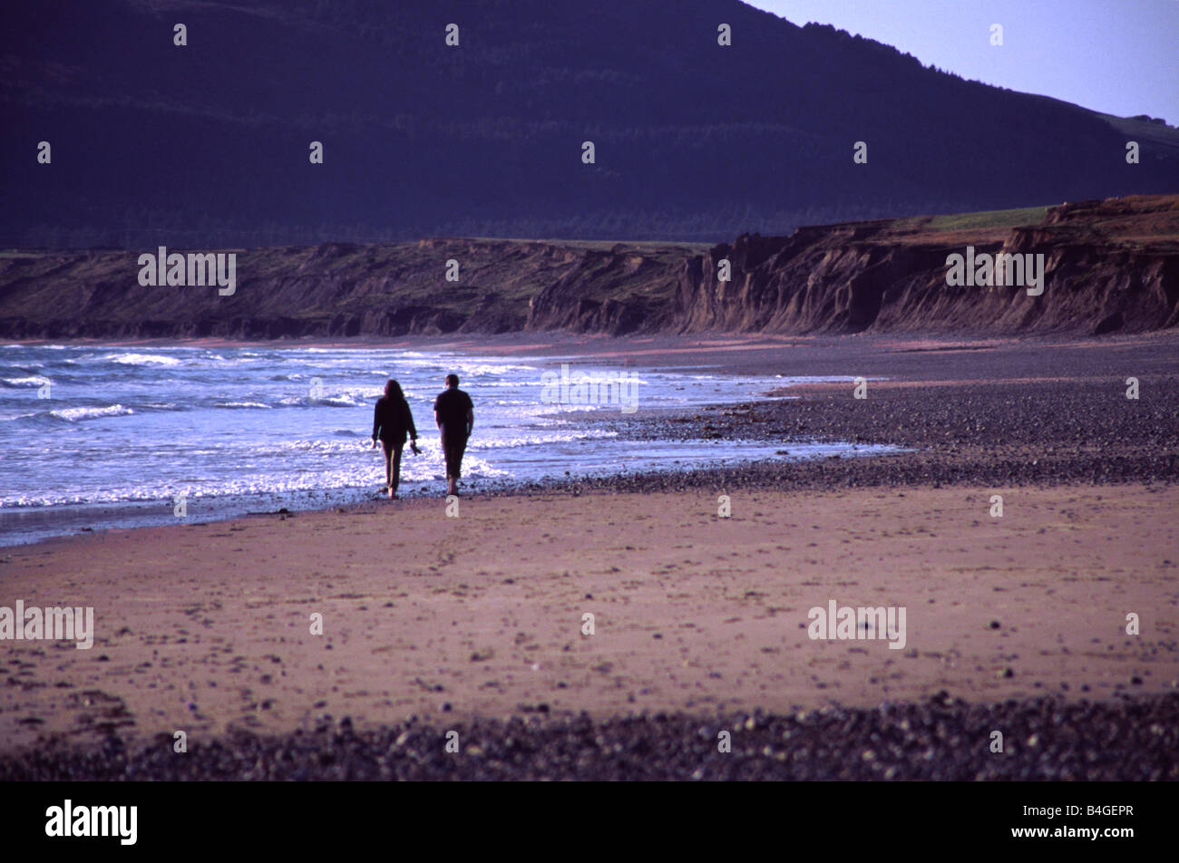 Due persone che camminano su Hell's Mouth Beach, il Galles del Nord Foto Stock