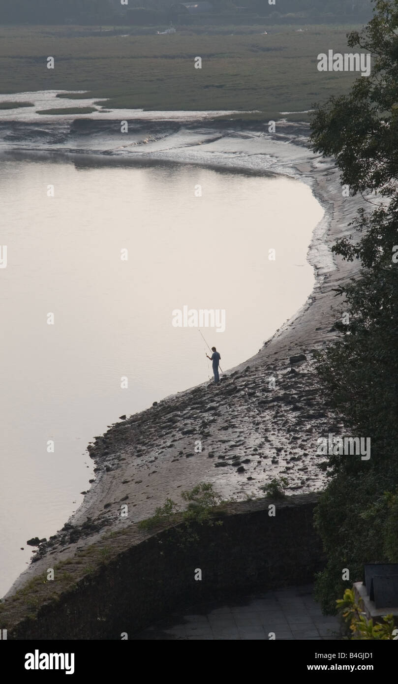 Un pescatore solitario sul fiume Taff mudbanks, Laugharne, Carmarthen, Wales, Regno Unito Foto Stock