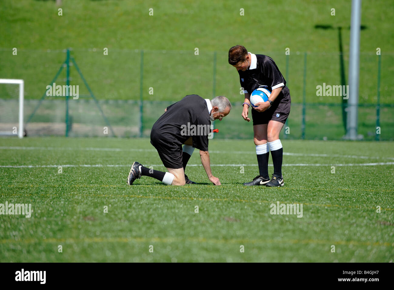 Due arbitri ispezionare un astro turf passo prima di una partita di calcio. Foto Stock