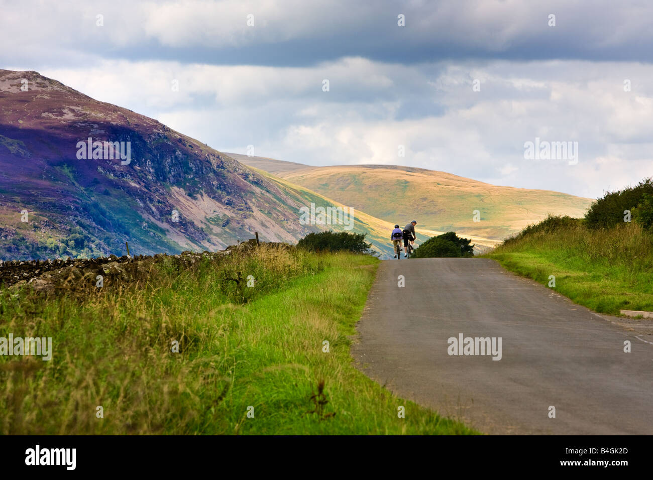 Due ciclisti in bicicletta su una strada aperta nel Lake District inglese, Cumbria, Inghilterra, Regno Unito Foto Stock