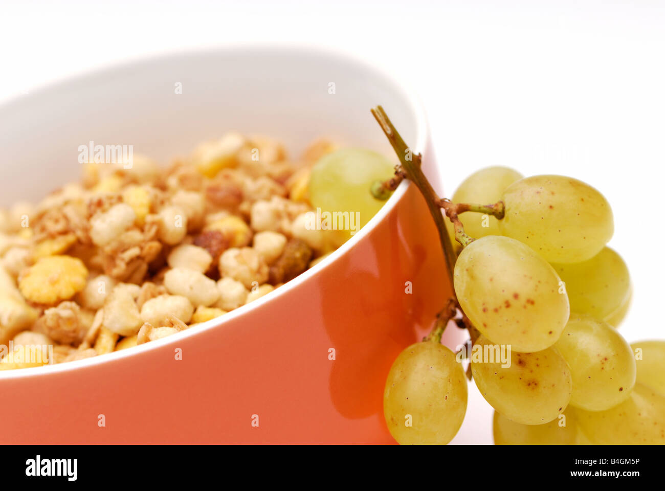 Una sana prima colazione, grappolo di uva in una ciotola di muesli. Sfondo bianco, il fuoco selettivo, raccolto orizzontale. Foto Stock