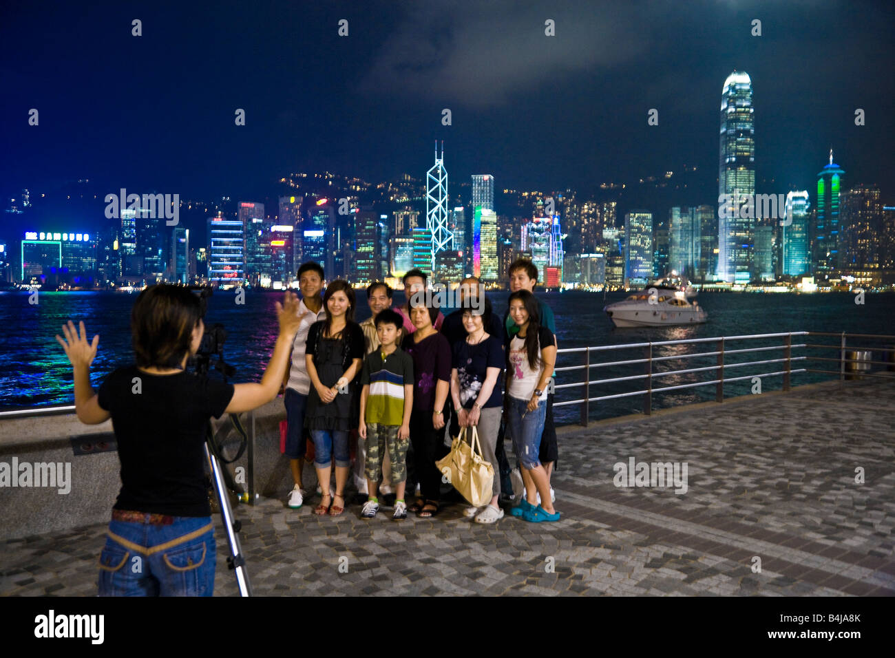 Gruppo di popoli asiatici in posa per il fotografo di Notte sulla passeggiata di Kowloon con luci dell'Isola di Hong Kong dietro JMH3312 Foto Stock