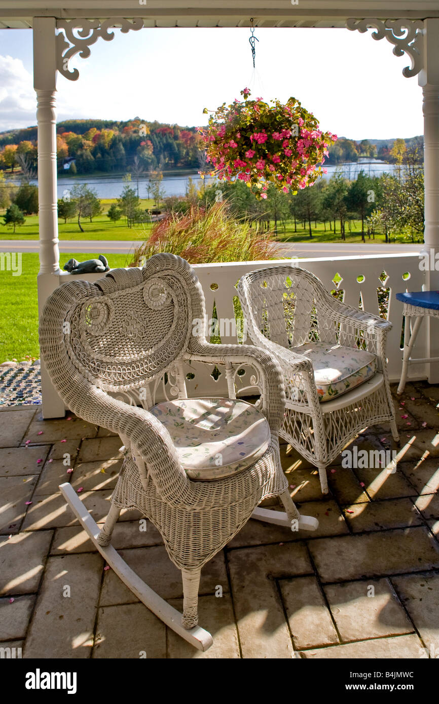 Nel tardo pomeriggio sole risplende sulla vecchia moda sedie di vimini sotto il portico di una casa rurale in Michigan nota i colori autunnali Foto Stock