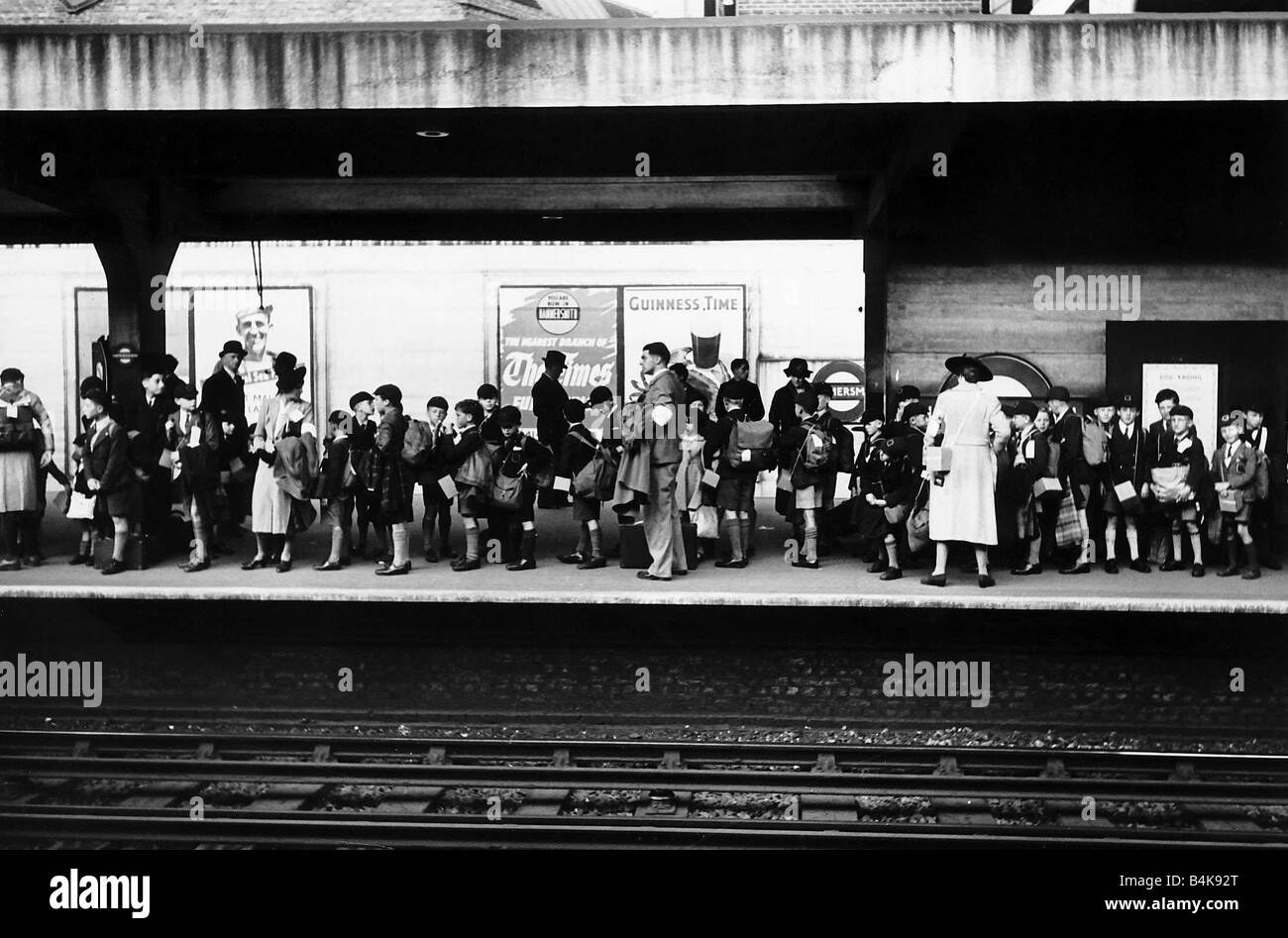 Gli allievi e i loro insegnanti in attesa alla stazione di Hammersmith London per essere evacuate per il paese durante il WW2 Foto Stock