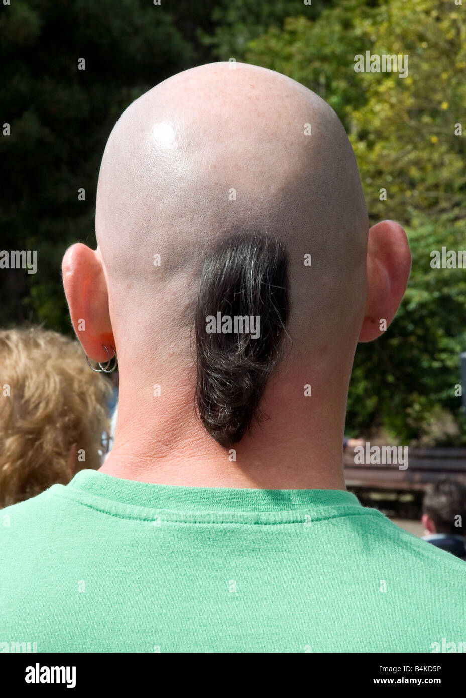 Ciuffo di capelli lunghi sul retro dell uomo con la testa rasata Foto Stock