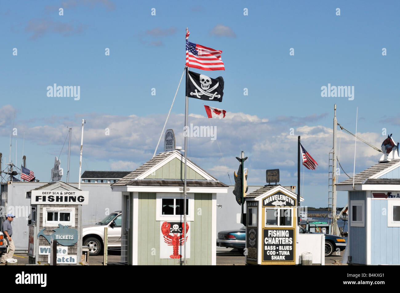 Fila di charter di pesca cabine biglietto sul molo con americani, canadesi e bandiere pirata sulla giornata di sole nel porto di Plymouth, MA USA Foto Stock