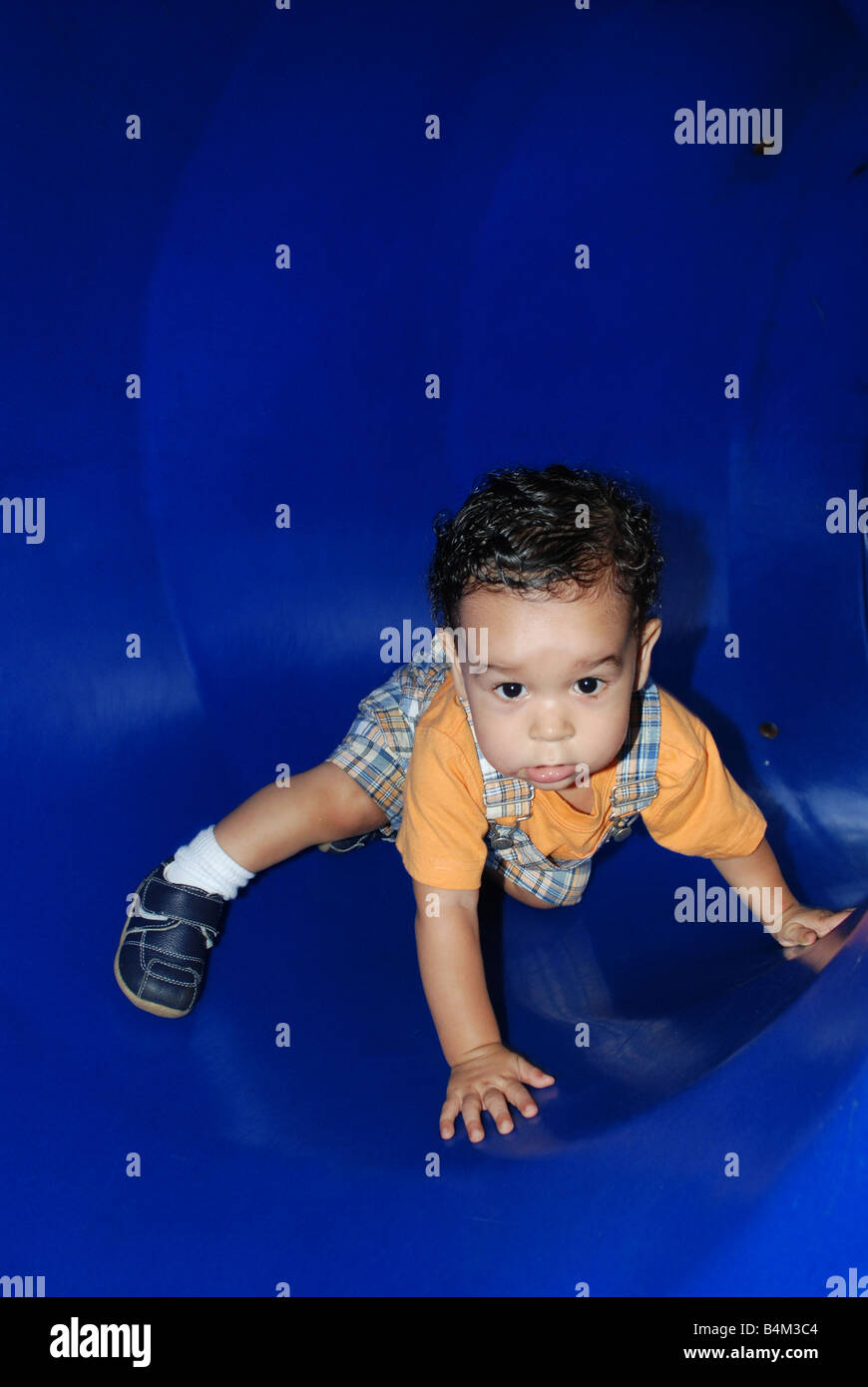 Un bambino è sorpreso mentre egli cammina dentro il blu parco giochi tubi. Foto Stock