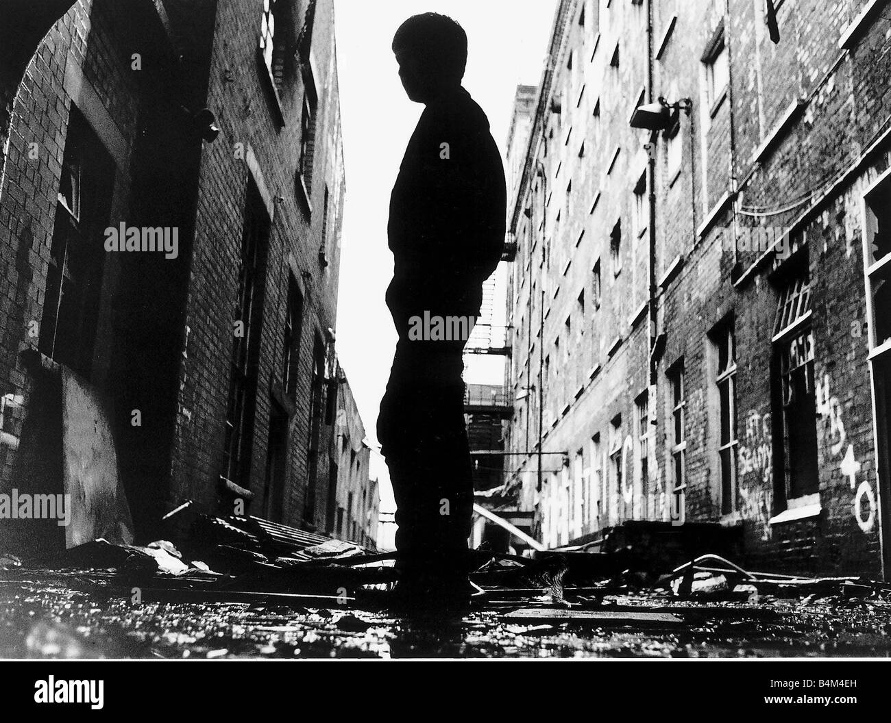 Un bambino gioca tra le macerie di Falls Road a Belfast dopo una notte di disordini Foto Stock