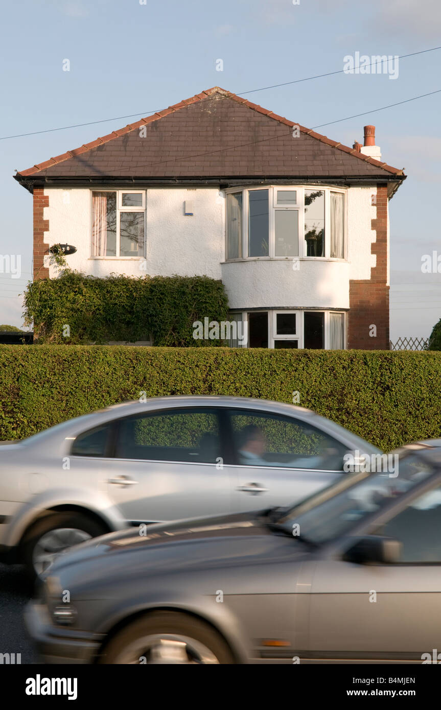 Cars driving passato una staccata casa suburbana Preston Inghilterra LANCASHIRE REGNO UNITO causando il rumore di disturbo di inquinamento Foto Stock