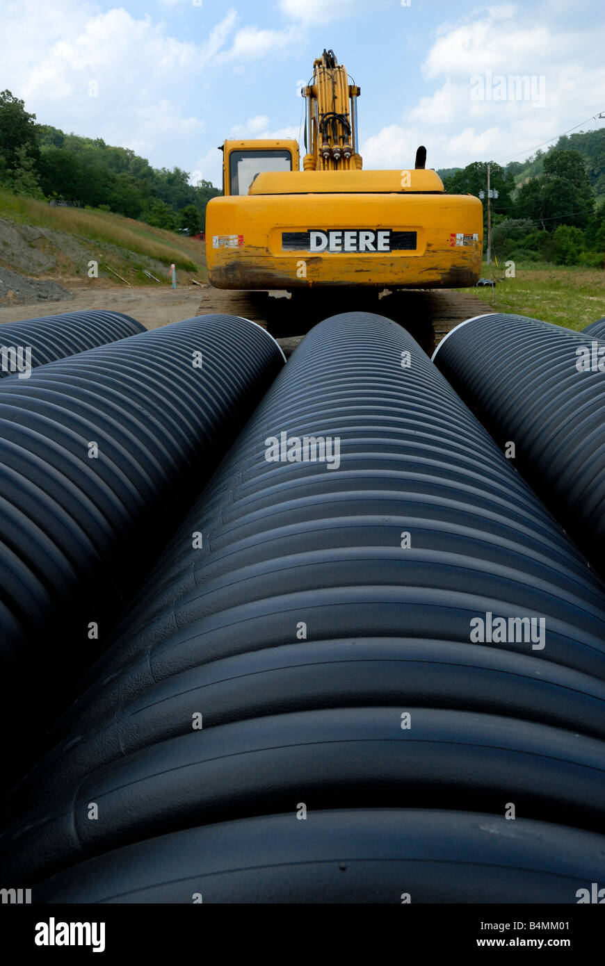 Un John Deere escavatore di costruzione in mezzo lungo le tubazioni di costruzione Foto Stock