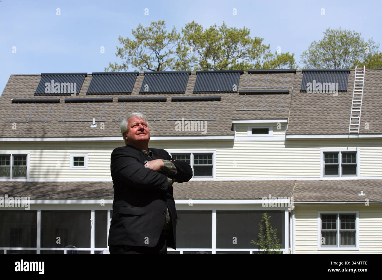 Un uomo con la sua casa che dispone di pannelli solari sul tetto che fornisce energia pulita e rinnovabile in Connecticut USA Foto Stock