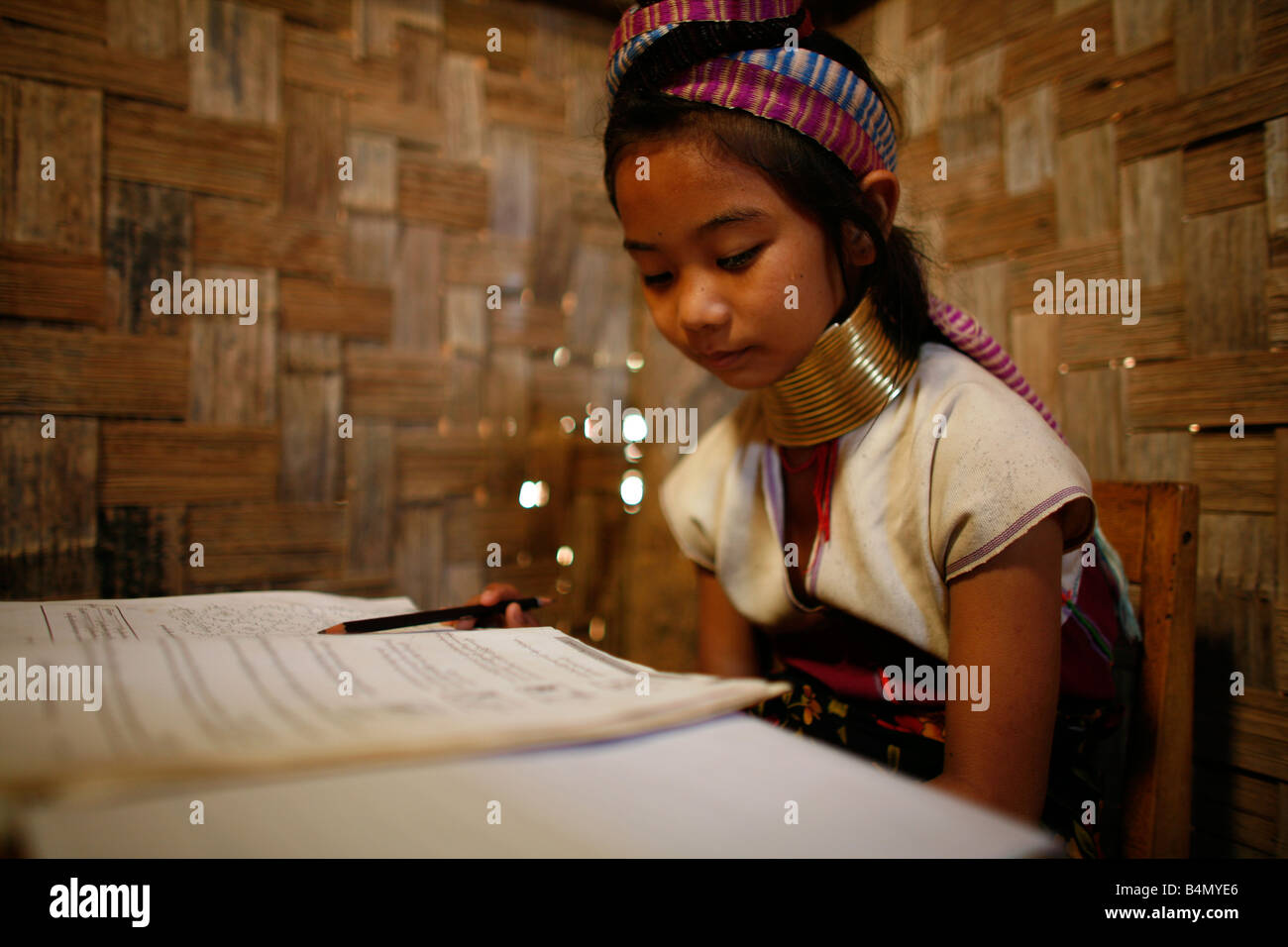 Primo piano di una giraffa di giovani ragazze la lettura a scuola di circa 300 profughi birmani in Thailandia sono membri del gruppo indigeno noto come Longnecks il più grande dei tre villaggi dove la Longnecks live è chiamato Nai Soi situato vicino a Mae Hong Son City Longnecks usura degli anelli di metallo sul loro collo che spingono la clavicola verso il basso e si estendono il collo sono una attrazione turistica turisti visitano Nai Soi per scattare foto di Longnecks e comprare il loro artigianato i villaggi sono criticati dalle organizzazioni per i diritti umani come umana giardini zoologici Foto Stock