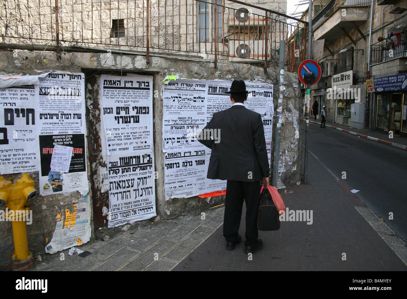 Un Ebreo Orthdox uomo legge annunci nella città vecchia di Gerusalemme Foto Stock