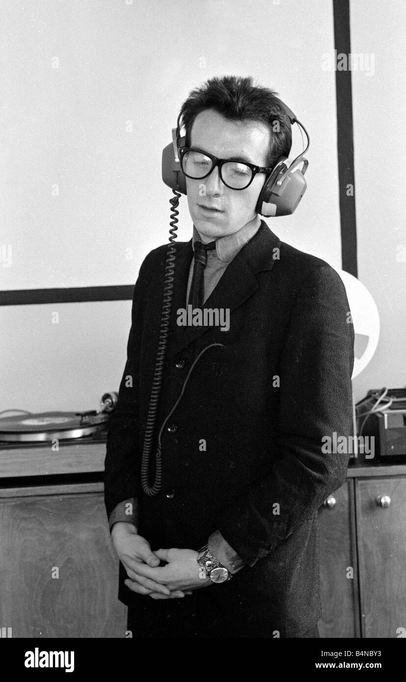 Elvis Costello la sensazione più recente sulla scena musicale in piedi in studio di registrazione con le cuffie Foto Stock