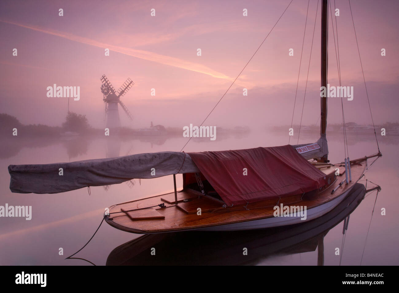 Il mulino a vento di Thurne e un Misty River Thurne all alba del Norfolk Broads con un legno tradizionale barca a vela in primo piano Foto Stock