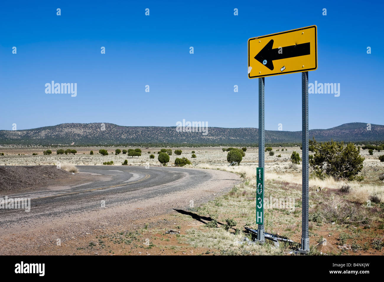 Cartello giallo che mostrano la direzione accanto a una strada Foto Stock