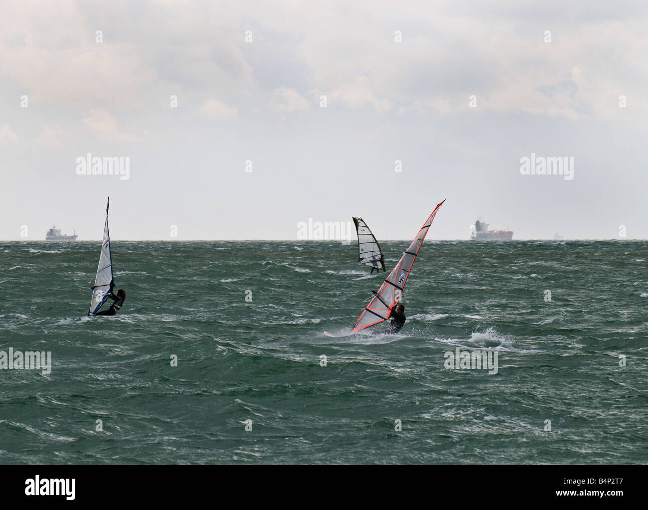 Tre windsurfisti del Solent con spedizioni in lontananza. Foto Stock