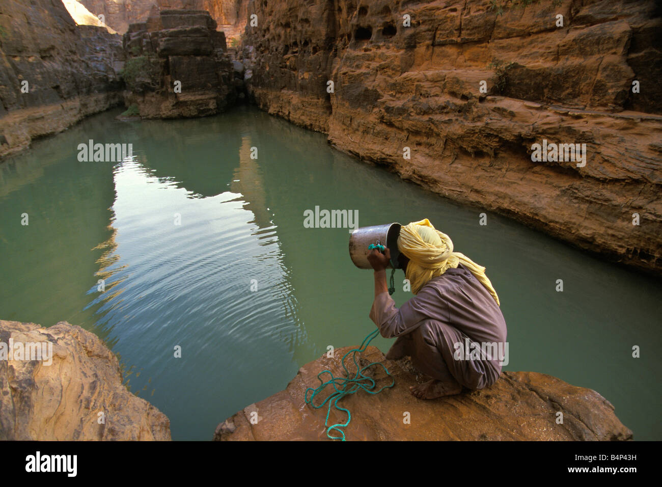 Algeria Djanet NP Tassili n Ajjer UNESCO World Heritage Site uomo della tribù Tuareg acqua potabile da pozzo o GUELTA Sahara Foto Stock