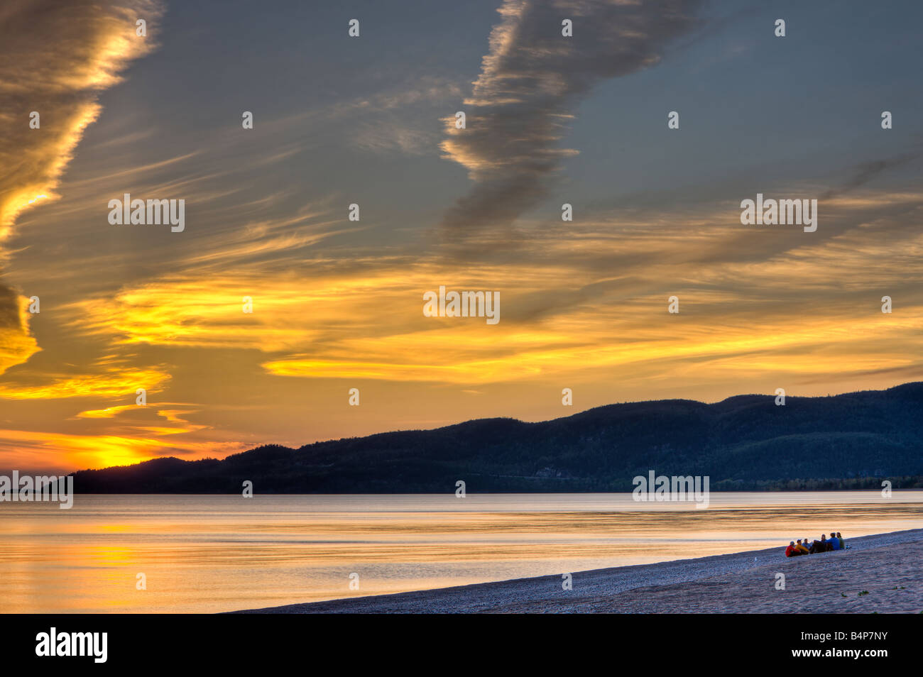 Gruppo di persone sedute sulla spiaggia nella baia di Agawa al tramonto, Lago Superiore, Lago Superior parco provinciale, Ontario, Canada. Foto Stock
