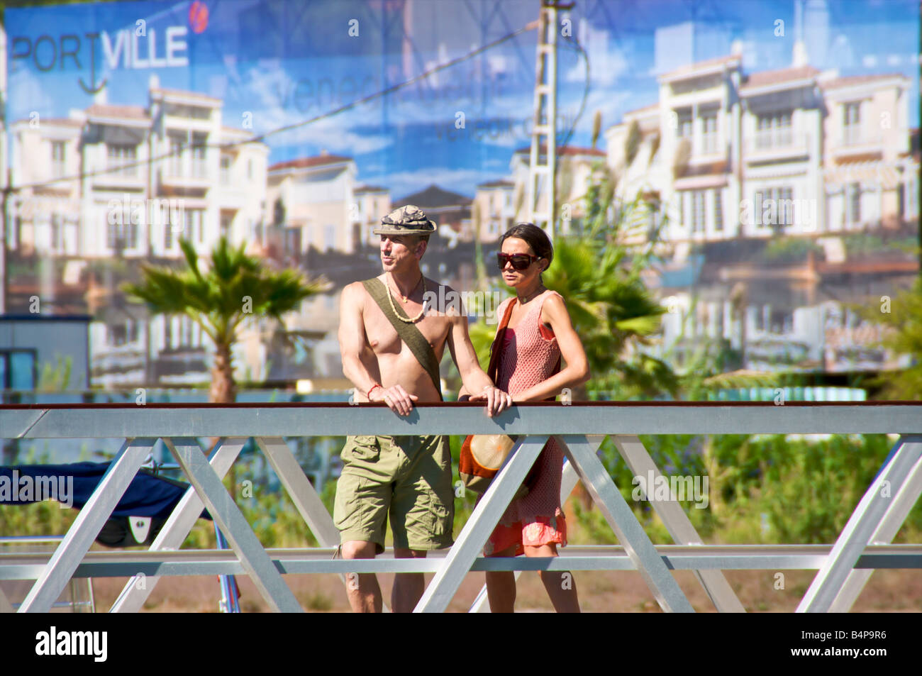 L uomo e la donna in piedi sul ponte del Porto Turistico di Goçek Turchia con il nuovo centro commerciale come sfondo. Foto Stock