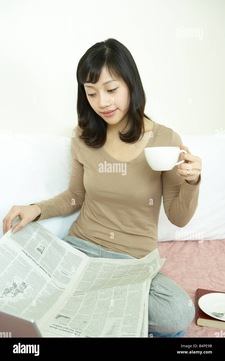 Giovane donna con una tazzina di caffè quotidiano di lettura Foto Stock