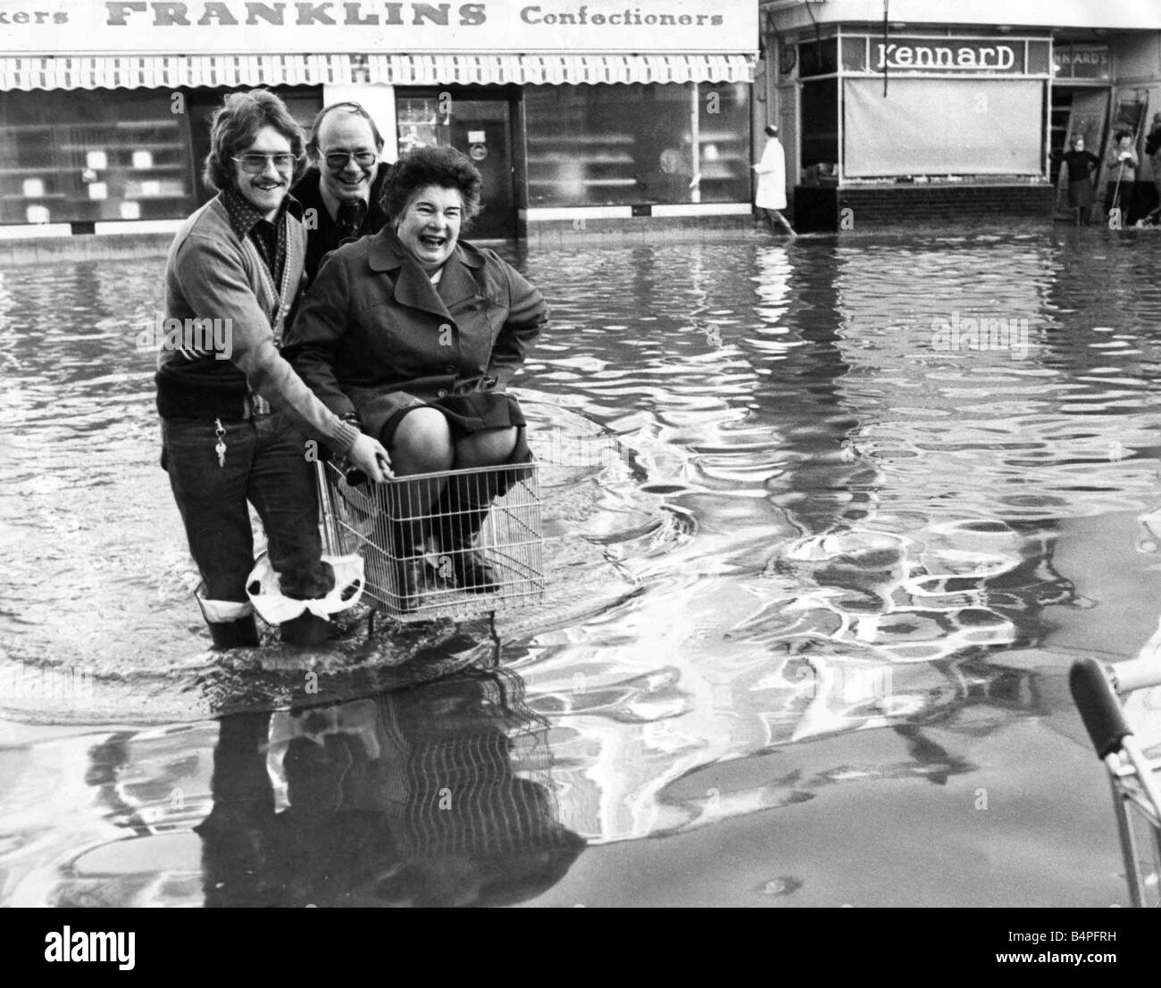 Il personale dell'allagato fuori il supermercato Tesco nel cantone di Cardiff di trovare un nuovo modo per mantenere i piedi asciutti come essi arrivano per il lavoro e la grande pulizia fino 27 dicembre 1979 Foto Stock