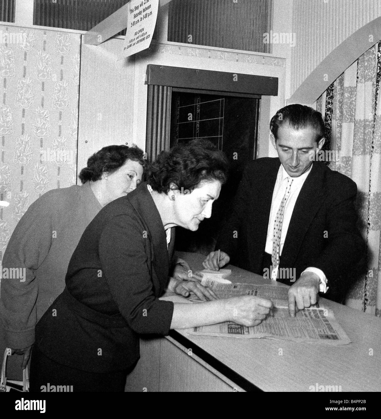 Una donna punter a studiare la forma guida prima di piazzare una scommessa in un negozio di scommesse su Caledonian Road a Londra Giugno 1961 Foto Stock