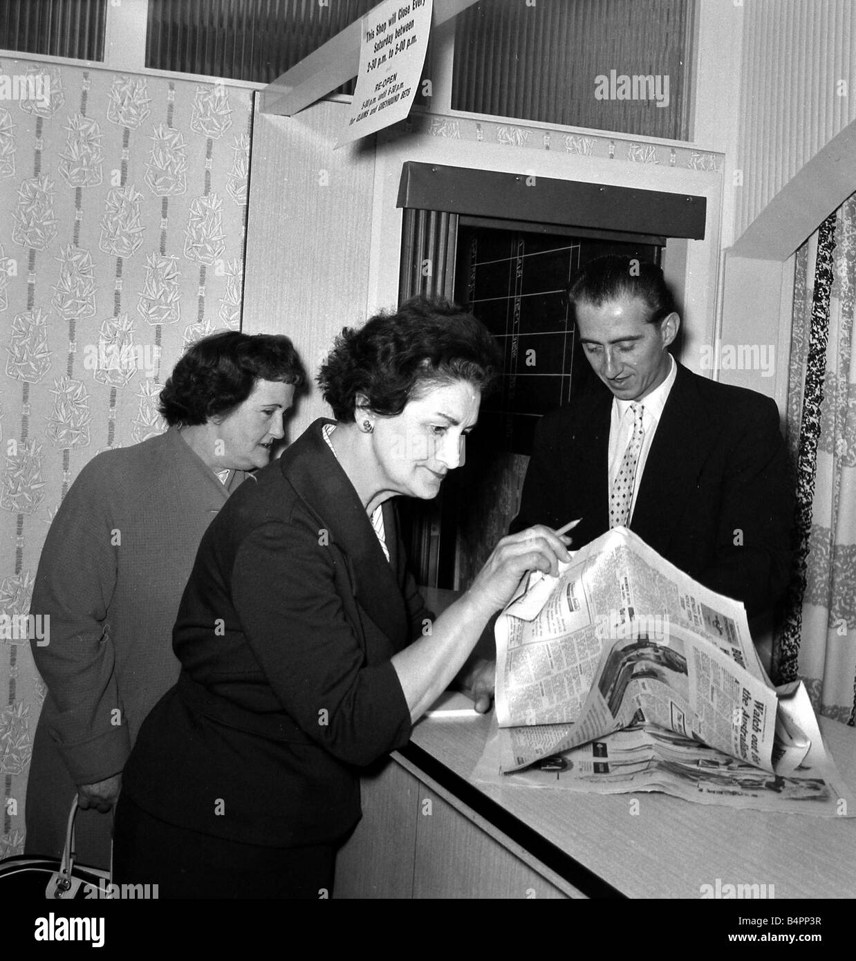 Una donna punter a studiare la forma guida prima di piazzare una scommessa in un negozio di scommesse su Caledonian Road a Londra Giugno 1961 Foto Stock