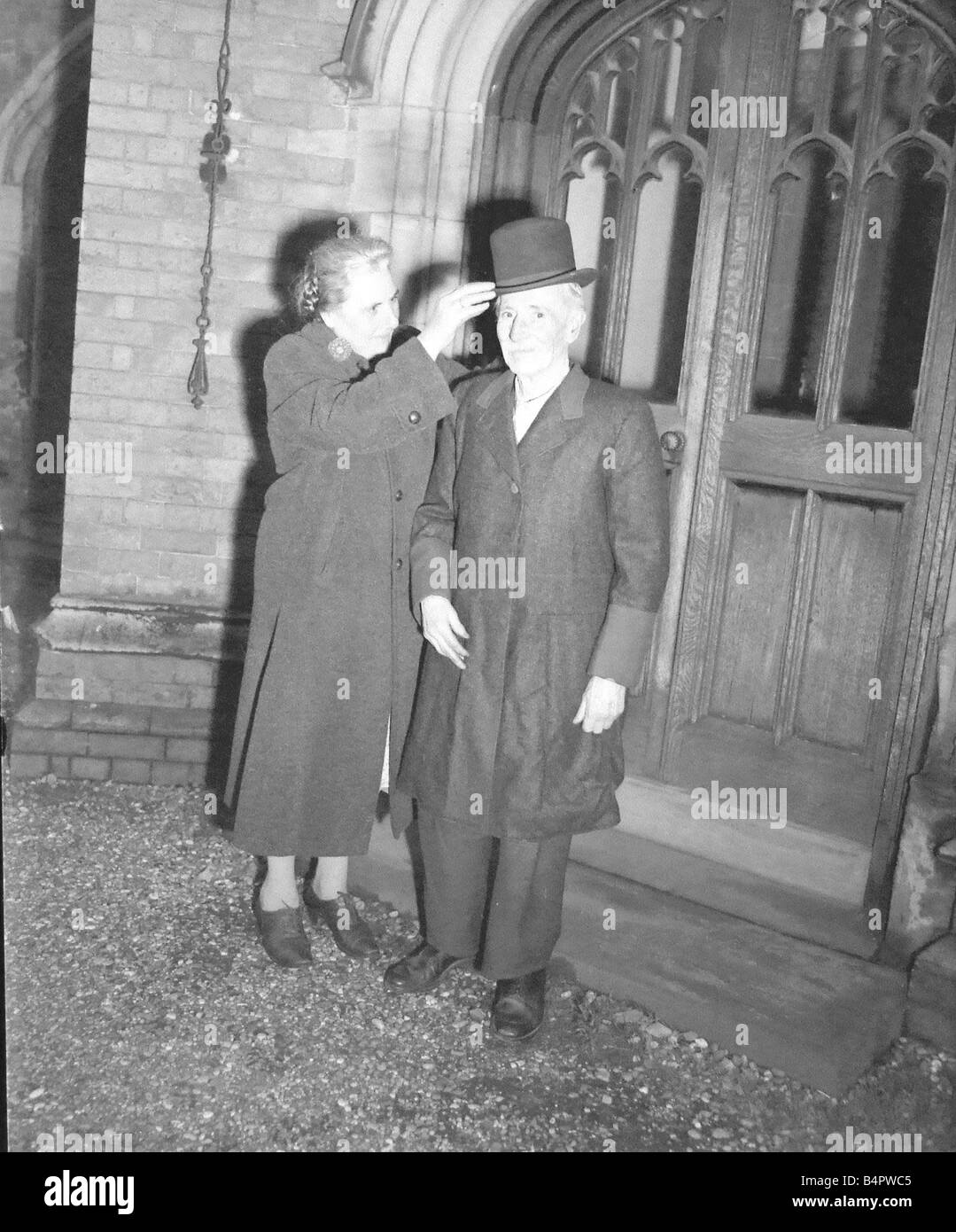 Vecchia coppia al di fuori di una chiesa in Bedworth anziana signora mettendo un cappello su un uomo anziano Nov 1958 Foto Stock