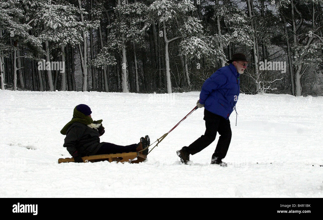 Neve sulle Lickey Hills Birmingham un uomo tira una donna su di una slitta che lasciano le colline Foto Stock