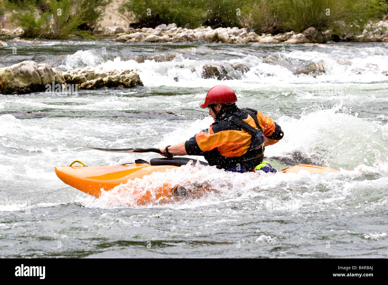 Whitewater kayaker navigando in onda su grado 3 rapida Foto Stock