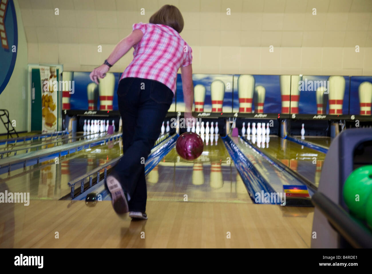 Una donna bocce di una sfera in una ten pin bowling alley. Foto Stock