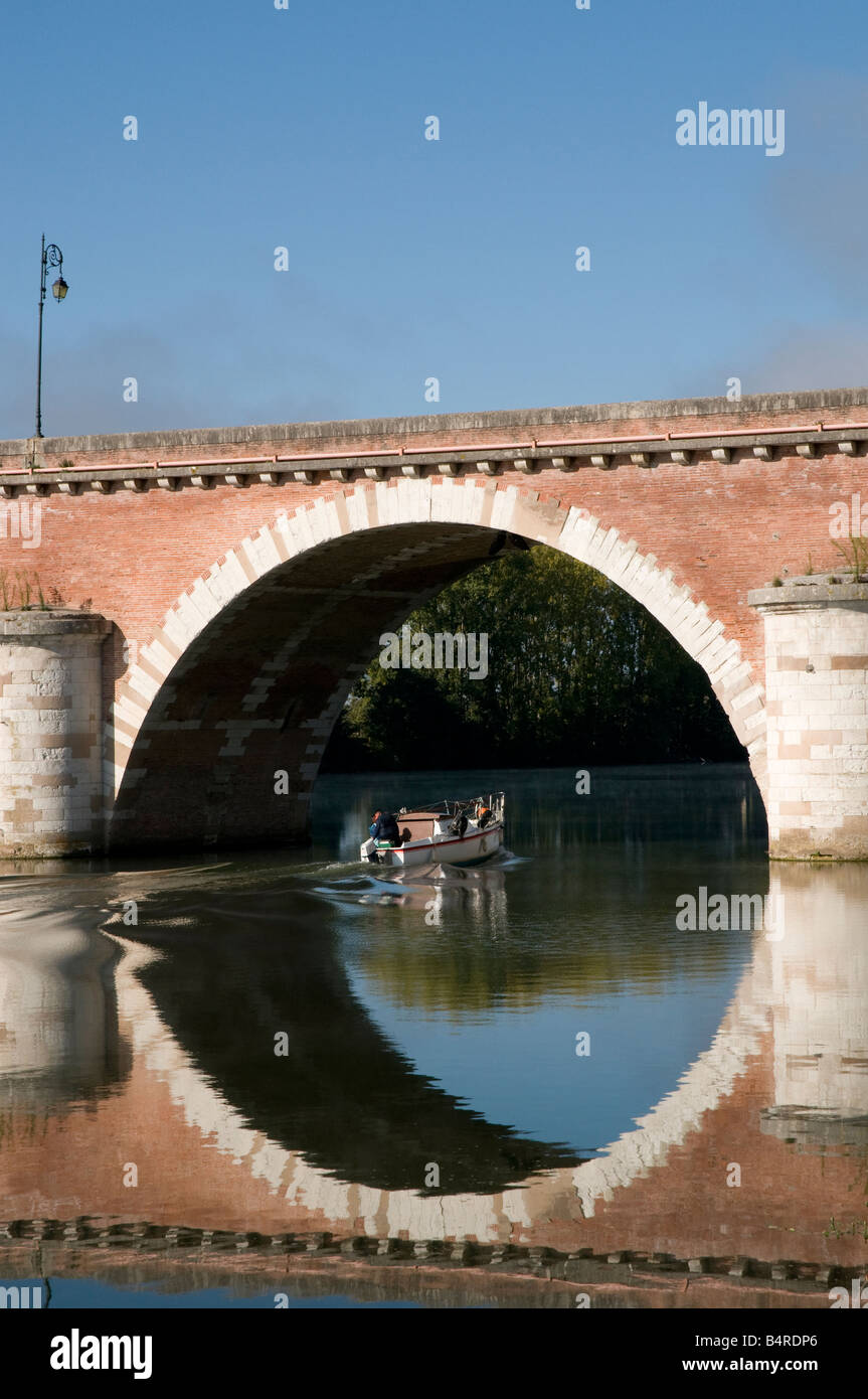 La Francia. Perfetto riflessione circolare in acqua della barca passando sotto l'arco in ponte sul fiume Tarn a Moissac Foto Stock