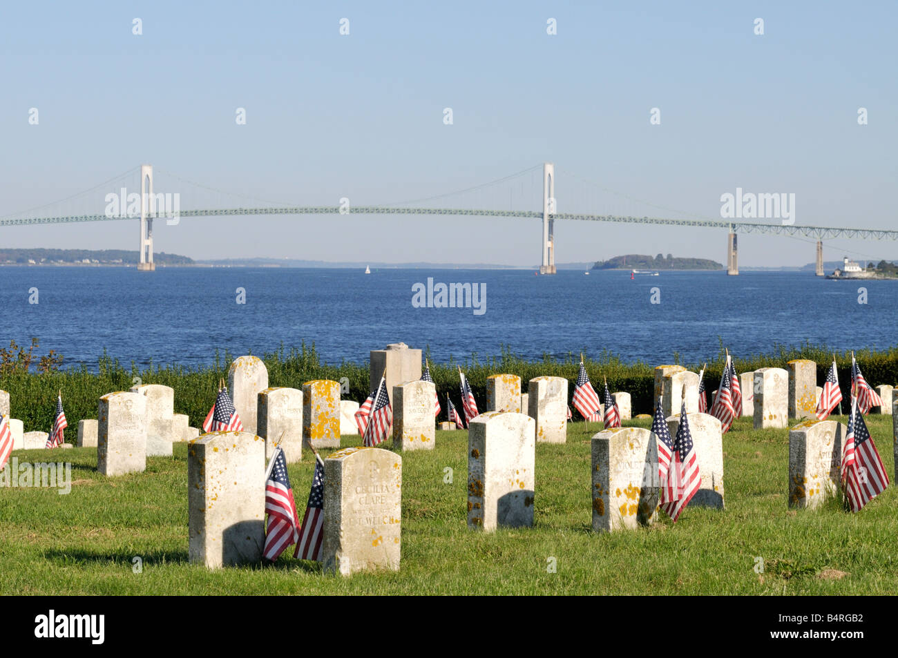 Cimitero storico con bandierine americane in Fort Adams State Park Newport Rhode Island con Pell Bridge e l'oceano in background Foto Stock