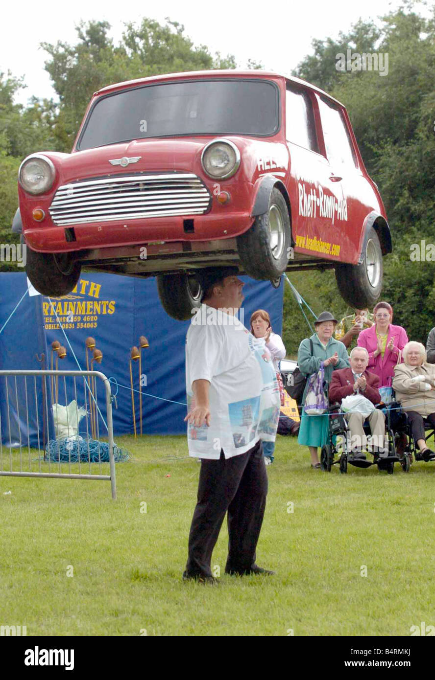 Su di me " ead ;John Evans dal Derbyshire equilibra una Mini auto sulla sua testa al saluta verde estate annuale Giornata di divertimento.; Foto Stock