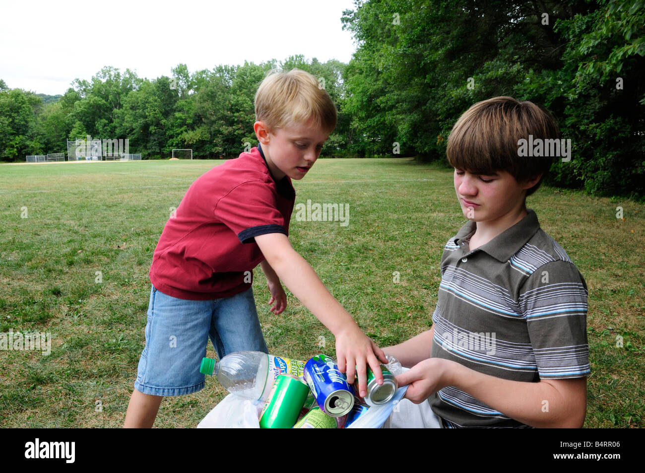Due ragazzi di prelevamento rifiuti riciclabili in un campo o in un parco Foto Stock