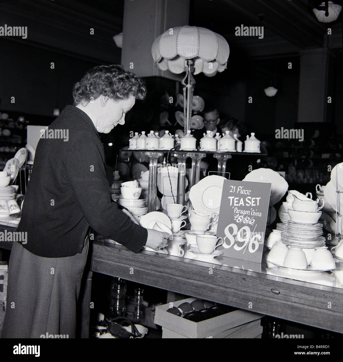 Una signora anziana in cerca di occasioni durante le vendite di gennaio a Derry e Toms shop in Kensington High Street London Dicembre 1957 Foto Stock