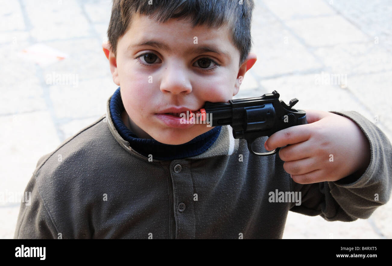 Un giovane ragazzo arabo punti una pistola giocattolo a questa bocca nel mercato vicino alla porta di Damasco a Gerusalemme la città vecchia. Foto Stock