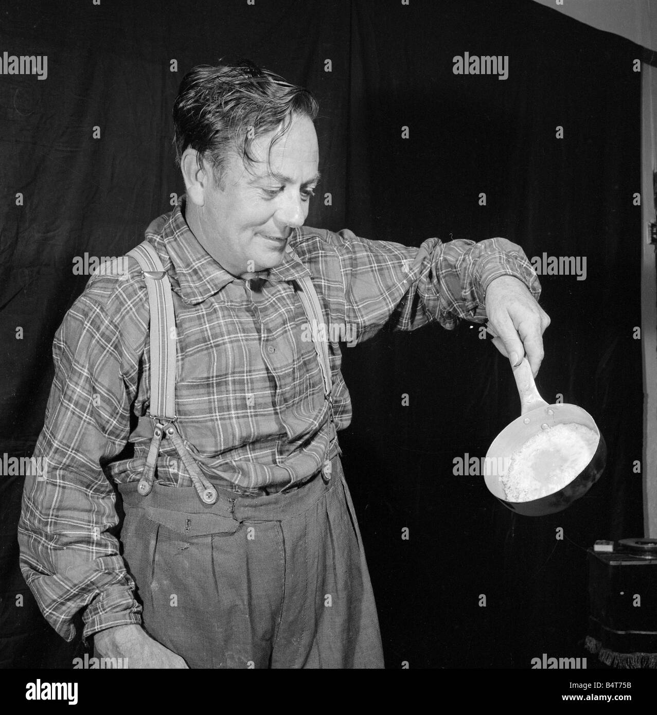 In Hot Seat Frank Batson fries un uovo sul dorso di Neville di legno per dimostrare le proprietà ignifughe del asbestoes Nevillie è visto qui a mangiare le uova cotte sul suo retro circa 1955 Foto Stock