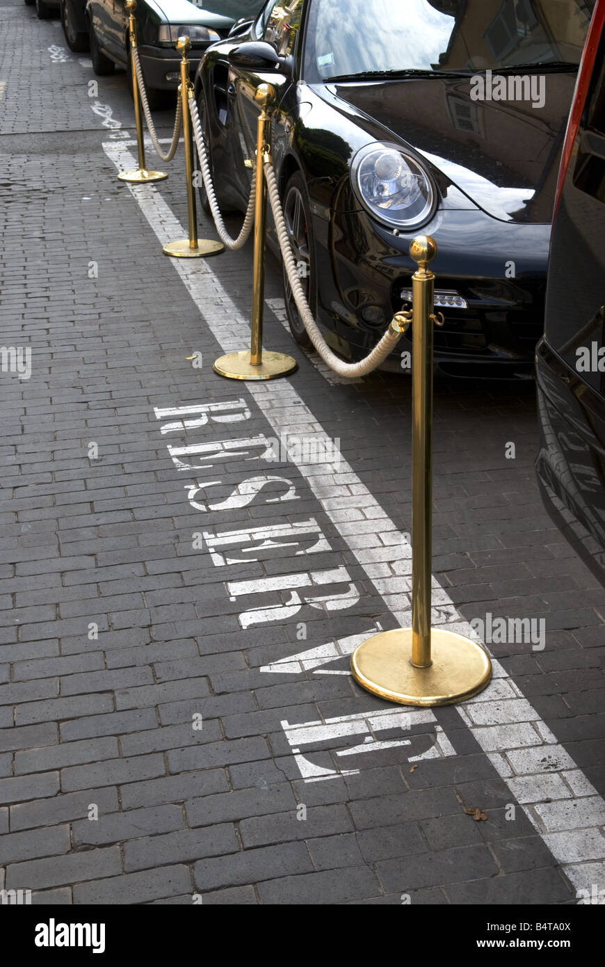 Guardando verso il basso in corrispondenza della parola "servire" impresse sulla strada accanto a parcheggiate automobili di lusso isolato di fronte all albergo di classe Foto Stock