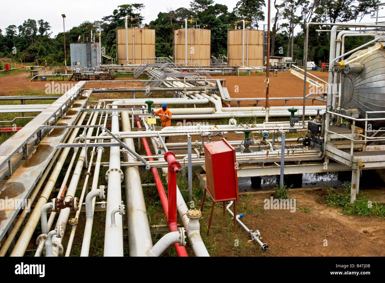 Olio Onshore impianto di lavorazione che mostra le tubazioni con olio di un addetto alla produzione di effettuare interventi di manutenzione, il Gabon Foto Stock