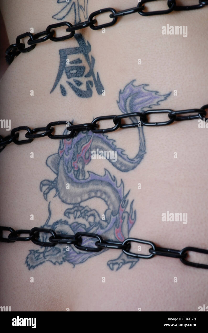 Tatuaggio di un drago blu e kanji legato in catene di nero Foto Stock