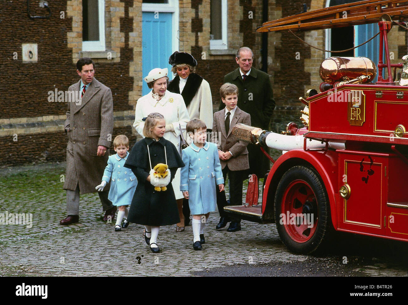 La regina Elisabetta 11 Gennaio 1988 con i suoi nipoti Zara Phillips Peter Phillips il principe William e il principe Harry la Principessa Diana e il Principe Carlo guardando un motore fire anche il Principe Filippo C T Roy Brit Queen Elizabeth Attualità n.1 Foto Stock