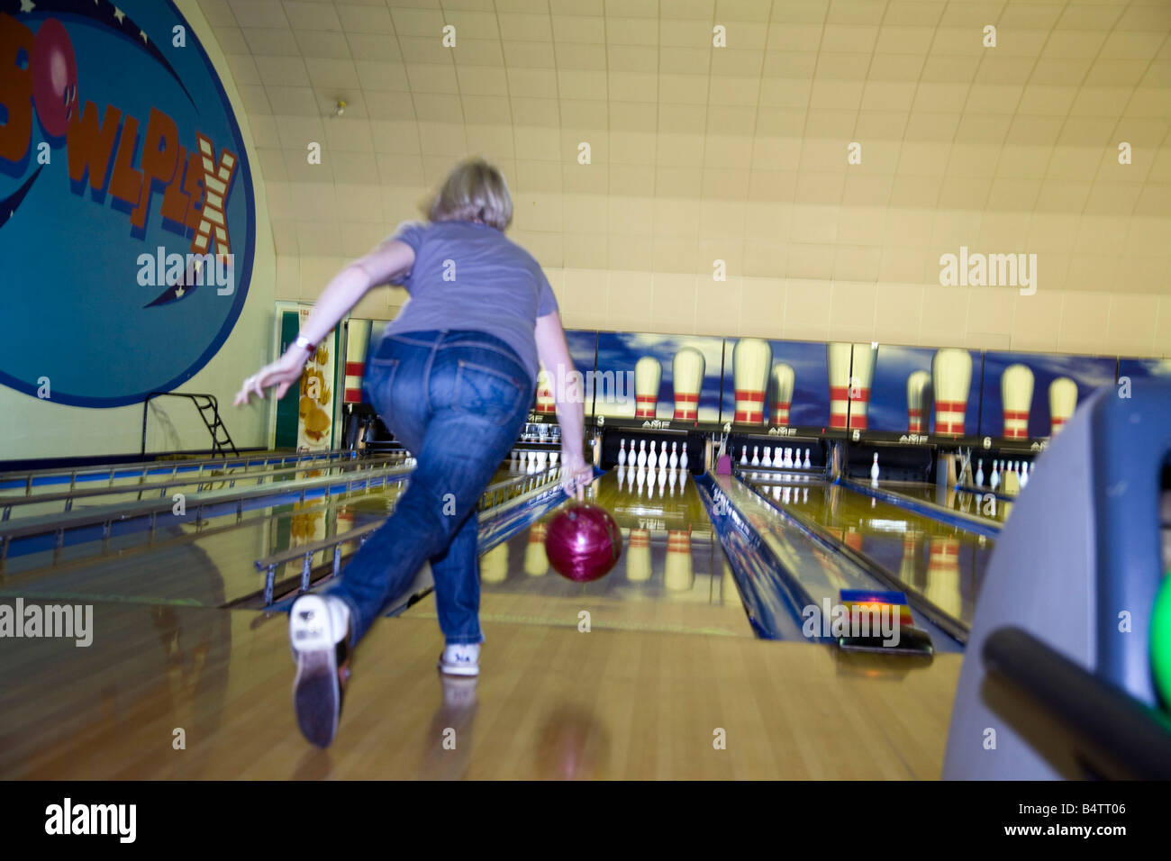 Una ragazza di bocce di una sfera in una ten pin bowling alley. Foto Stock