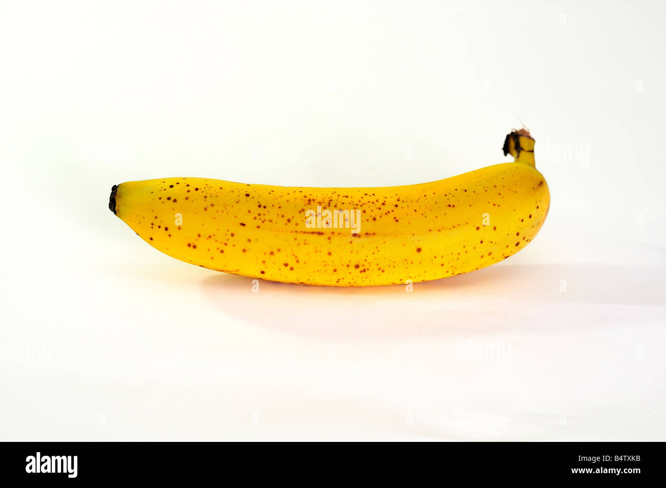 Un intero con la buccia di banana matura su uno sfondo bianco. Foto Stock