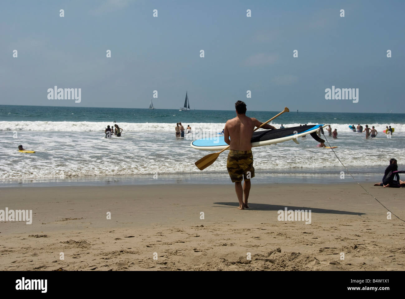 La spiaggia di Santa Monica CA folla di persone rilassante, nuotare, prendere il sole e divertirsi con la tavola da surf paddle spiaggia di sabbia a piedi, wave Foto Stock