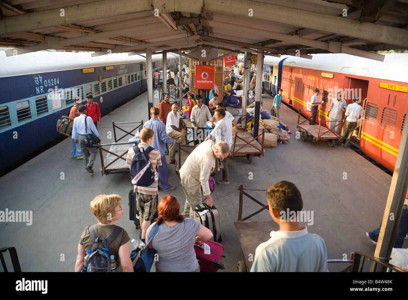 Una stazione affollata piattaforma con due treni a Nuova Delhi stazione ferroviaria, India Foto Stock